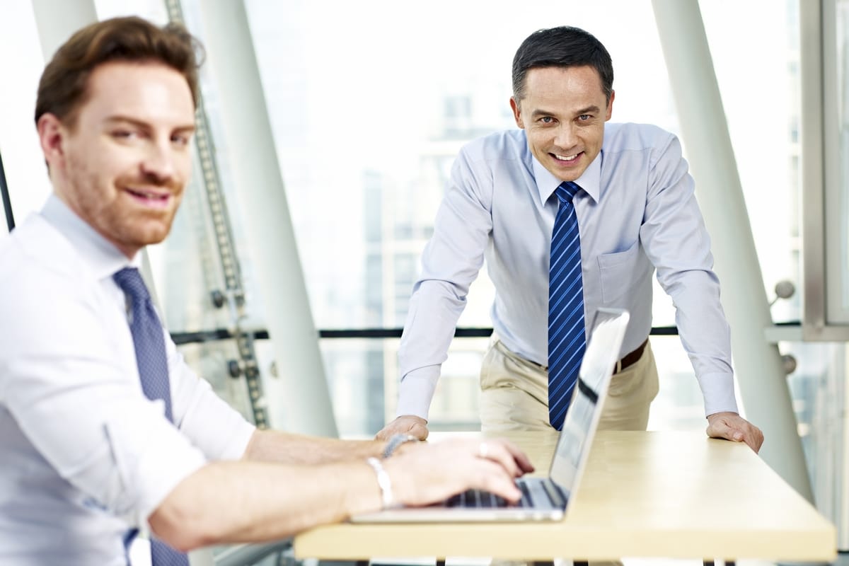 two caucasian business executives working in office looking at camera smiling. ** Note: Shallow depth of field