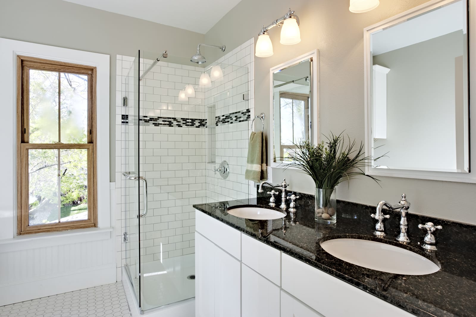 Bright white remodel bathroom. Glass shower and granite counters.